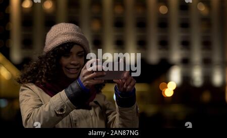 Bella Signora in posa e sorridente, tenendo selfie immagine sullo smartphone moderno Foto Stock