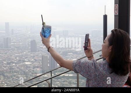 Bangkok, Tailandia - 21 dicembre 2019: Donna di scattare una foto della bevanda blu contro il paesaggio urbano di Bangkok. Foto Stock