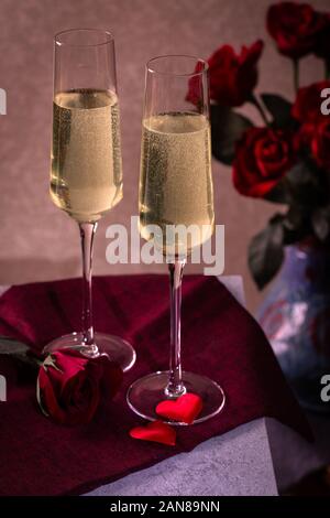 Due bicchieri di champagne e rose rosse su un tavolo. Il giorno di San Valentino tema Foto Stock