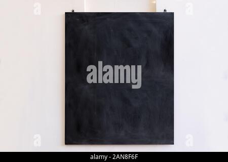 Blackboard segno appesa sul muro bianco sullo sfondo. Black blank board, istruzione scolastica segno, modello per messaggio, spazio di copia Foto Stock