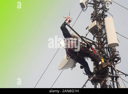 Elettricista uomo o alpinista arrampicata su palo antenna per ispezione. abstract sfondo verde per il testo Foto Stock