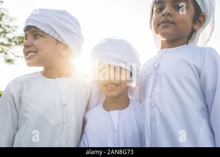 Bambini che giocano insieme a Dubai nel parco. Un gruppo di bambini che indossano kandura tradizionale abito bianco da emirati arabi Foto Stock