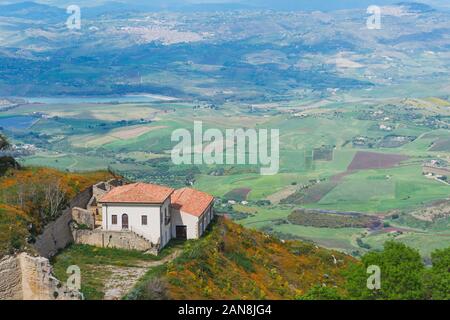 Un solitario hillside house con un tetto di tegole, nella distanza di un panorama di prati di campi e città distanti Foto Stock