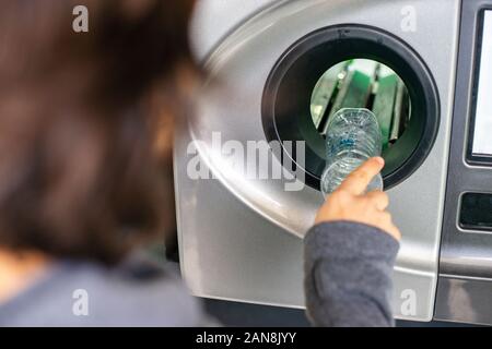 Donna in retromarcia della macchina distributrice di riciclare le bottiglie di plastica, concetto di ecologia Foto Stock