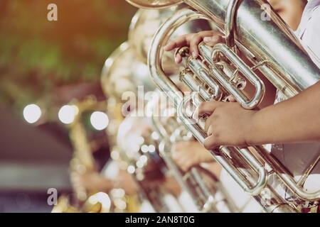 Studente di sesso maschile con gli amici di soffiare il eufonium con la banda per la performance sul palco di notte. Foto Stock