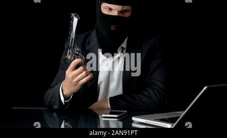 Mafiosi con la pistola utilizzando laptop, rompere in banca di sicurezza sistema di preparazione della criminalità Foto Stock