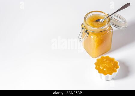 In casa deliziosa marmellata di frutta in un barattolo di vetro e ciotola su sfondo bianco. Copia dello spazio. Vista laterale. Foto Stock