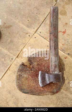 Taglio di ascia e sfaldatura Di Carne su fondo di legno . AX bloccato in un ceppo vicino al calderone in piedi su un falò . Blocco di tagliere e sfaldatura Di Carne Foto Stock