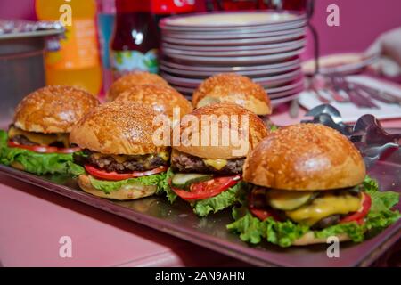 Splendidamente decorate catering per banchetti Tavolo con differenti hamburger hamburger panini su di una piastra sulla corporate compleanno . Mini o piccolo Burger Foto Stock