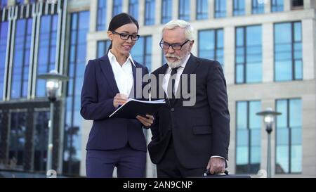 Giovane donna di affari e anziani boss per discutere i dettagli del contratto, il lavoro di squadra Foto Stock