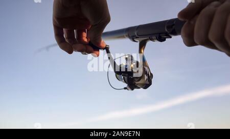 Mans mani pesca a spinning aspo, la cattura del pesce, l'ingranaggio e forniture, close up Foto Stock