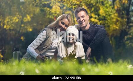 Famiglia tradizionale su picnic nel parco sorridente e guardando la telecamera, assicurazione Foto Stock