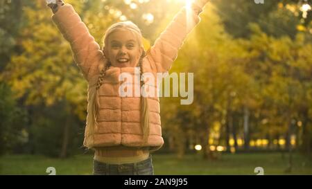 Happy School girl alzando le braccia in alto, gioia bella stagione autunnale, divertente Foto Stock