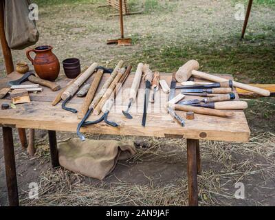 Macchine per la lavorazione del legno vecchio strumento mano: Piano in legno, scalpello ax, mazza, martello e in un laboratorio di falegnameria sporca sul tavolo rustico coperti con segatura Foto Stock