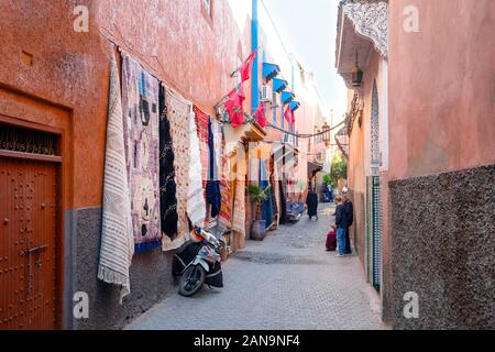 Strada stretta della vecchia medina con negozio di tappeti a Marrakech, Marocco Foto Stock