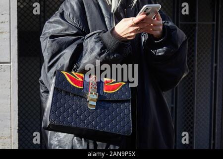 Milano, Italia - 12 gennaio 2019: Donna con Gucci nera Borsa in pelle con il rosso e il giallo di fiamme guardando smartphone prima di Etro fashion show, Milano F Foto Stock