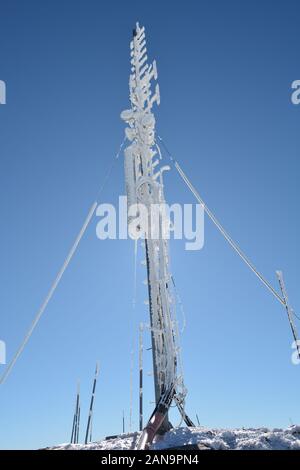 Congelati multi purpose antenna, ricoperta da brina sul picco di montagna, illuminata da dietro Foto Stock