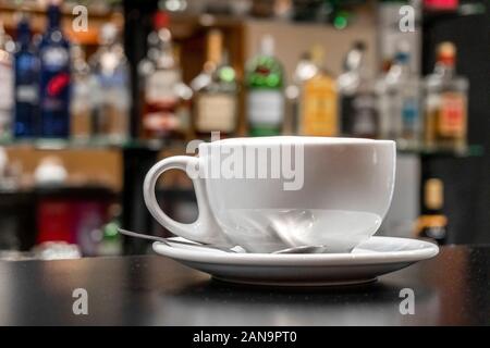 Caffè latte nella tazza bianca con argento cucchiaio da tè in bar Foto Stock