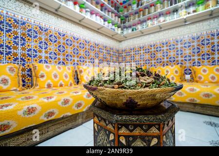 Interno marocchino con varietà di spezie su ripiani e tè alle erbe al centro della stanza Foto Stock