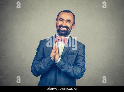 Ritratto di imprenditore soddisfatto uomo sorridente con mani giunte guardando a voi felice della fotocamera. Gara di misto modello barbuto isolati su grigio parete studio ba Foto Stock