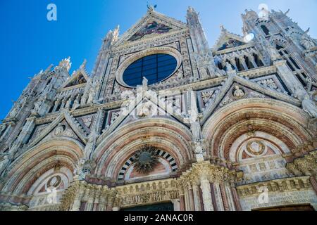 Facciata ovest della cattedrale di Siena con strisce alternate di colore bianco e verde-marmo nero con le sue tre portale, agendo come la principale porta d ingresso al D Foto Stock