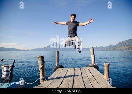 Giovane avventuriero saltando sul molo del lago Atitlan in Guatemala a sunrise Foto Stock