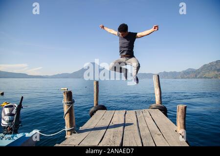 Giovane avventuriero saltando sul molo del lago Atitlan in Guatemala a sunrise Foto Stock