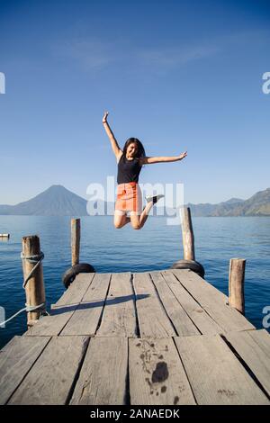 Giovane avventuriero saltando sul molo del lago Atitlan in Guatemala a sunrise Foto Stock