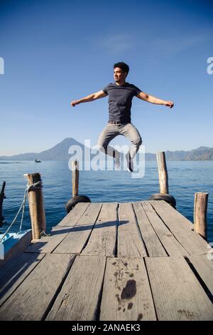 Giovane avventuriero saltando sul molo del lago Atitlan in Guatemala a sunrise Foto Stock