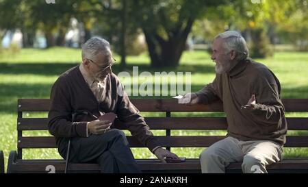 Coppia di amici a giocare a carte divertirsi nel parco, uno stile di vita attivo, il pensionamento Foto Stock