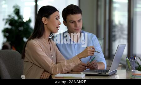 Multietnica i colleghi a discutere di un nuovo progetto alla ricerca del notebook, team aziendale Foto Stock