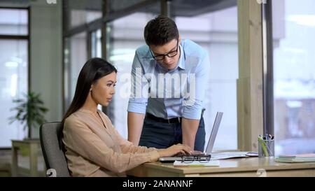 Il boss bello il controllo del lavoro di assistente femmina, i giornalisti che scrivono articolo Foto Stock