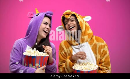 Amici di sesso femminile in funny pigiami divertendosi, gettando popcorn, felicità Foto Stock