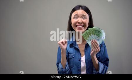 Estremamente donna felice di contenimento delle banconote in euro, buon stipendio, concetto di occupazione Foto Stock