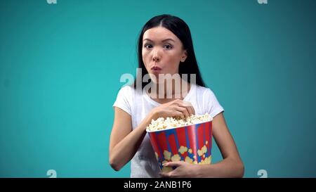 Donna concentrato masticare popcorn e guardare film avvincente nel cinema, concept Foto Stock