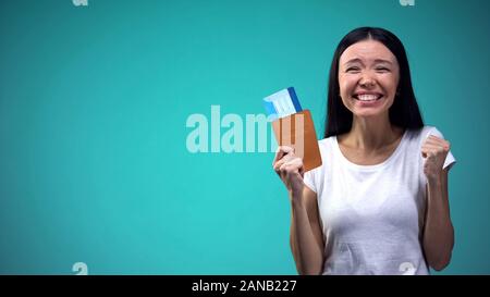 Excited donna holding passaporto con i biglietti in mano, vincendo tour vacanza Foto Stock