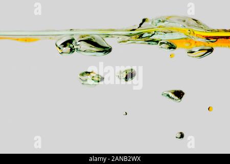 Close up di risalita di bolle d'aria nell'olio acqua versata isolato su bianco. Foto Stock