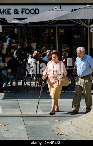 Una coppia anziana che gode di una soleggiata passeggiata Domenica pomeriggio in Plaza de la Campana Foto Stock