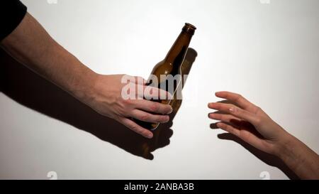 Dando a mano bottiglia di birra ad alcol addict con auto-inflitte braccio, dannoso vizio Foto Stock