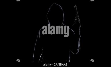 Silhouette di un serial killer in hoodie minacciando con la pistola, preparazione per omicidio Foto Stock