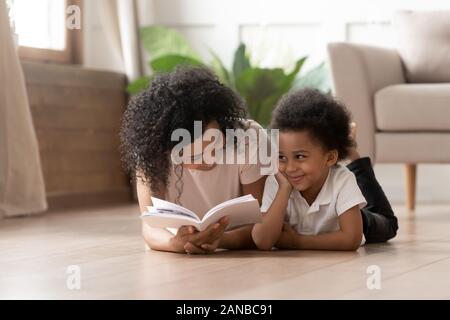 Carino curly black boy ascoltando storie divertenti. Foto Stock