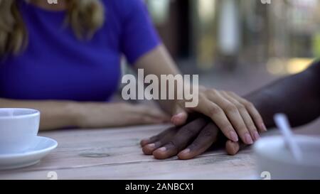 Ragazza caucasica toccando americano africano mano maschio, supporto e amore Foto Stock