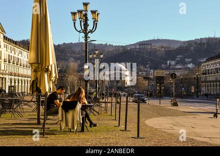 Una giovane coppia godendo il sole seduti in un caffè all'aperto in Piazza Vittorio Veneto con la Chiesa della Gran Madre di Dio, Torino, Piemonte, Italia Foto Stock