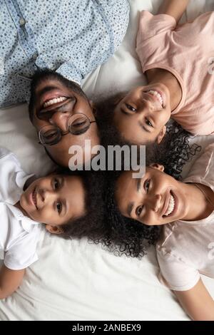 Felice famiglia nero recante un testa a testa sul letto. Foto Stock