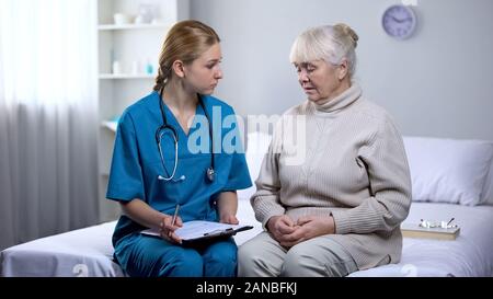 Esame medico paziente anziano, la scrittura di diagnosi in medical records, dolore Foto Stock