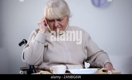 Infelice vecchia donna in sedia a rotelle che rifiuta di mangiare pranzo ospedale, sentirsi soli Foto Stock