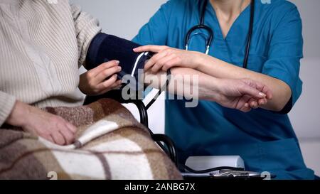 Terapista la misura della pressione del sangue di old Lady, esame sanitario, clinica Foto Stock