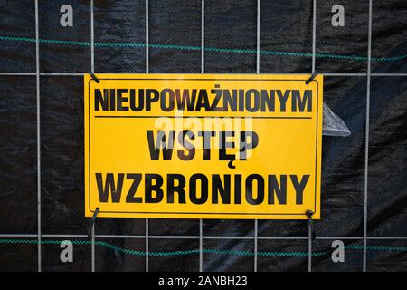 Cartellone giallo con l'iscrizione i n polacco: 'Accesso non autorizzato vietato' (nieupowaznionym wstep wzbroniony) appeso sulla rete della recinzione Foto Stock