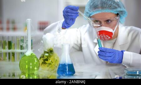 Biochimico versando il liquido oleoso in tubo con sostanza blu e reazione di controllo Foto Stock