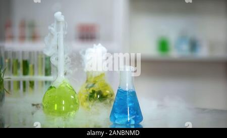 Multicolore di prodotti chimici liquidi in beute gorgogliamento e emettendo fumo, reazione Foto Stock